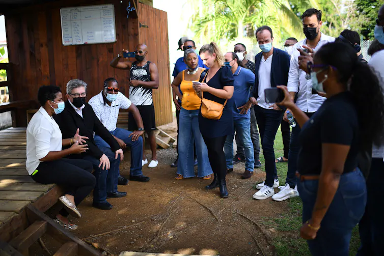 Jean-Luc Mélenchon discute avec des habitants et des représentants locaux à côté de la députée Mathilde Panot et du député européen Manuel Bompard dans le quartier populaire de Volga plage à Fort-de-France (France)
