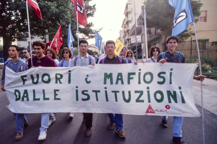 Group of people marching holding a white banner.