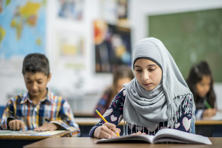 A Muslim student reads a book in class.