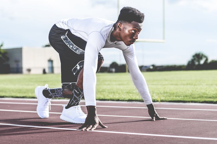 A man on a running track positioned to start a sprint