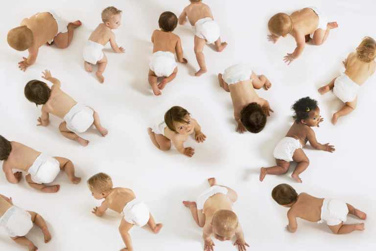 Numerous babies in diapers crawling in a white space
