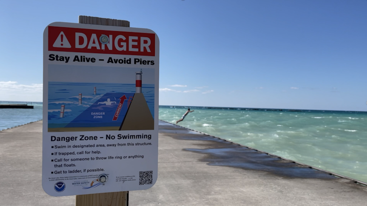 Boy jumping off jetty despite warning signs.