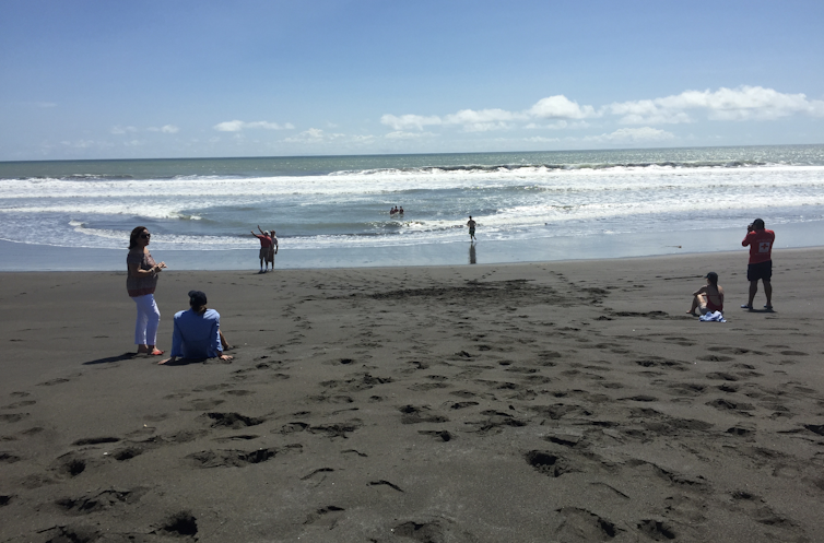 People sit on a beach directly in front of a rip current.