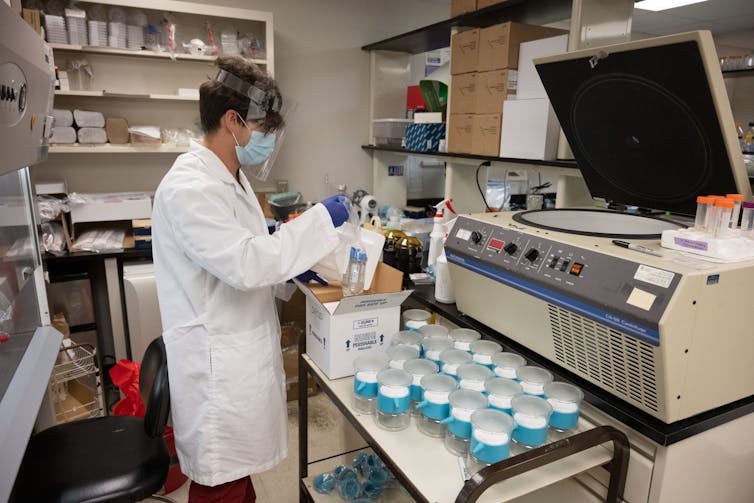 masked lab worker with glassware and lab equipment