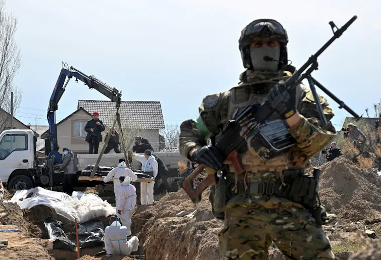 Un militaire ukrainien surveille la zone lors de l’exhumation de corps à Boutcha