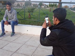 A man takes a photo of another man on his cellphone