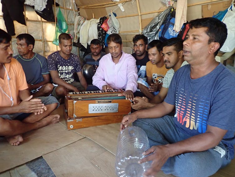 Men sit in a circle, cross-legged