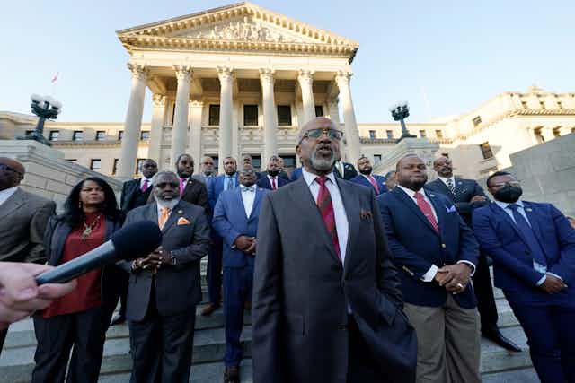Les leaders législatifs se tiennent sur les marches d'un bâtiment gouvernemental à Jackson, Mississippi. 
