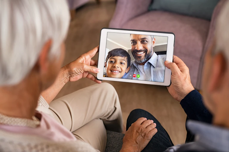 A tablet with a father and son is being held by two older adults.