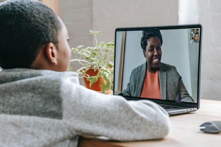 A boy is seen talking to a woman online.