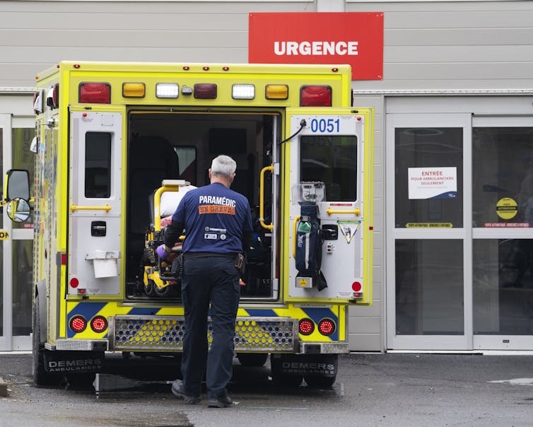 A paramedic loads a stretcher back into an ambulance.