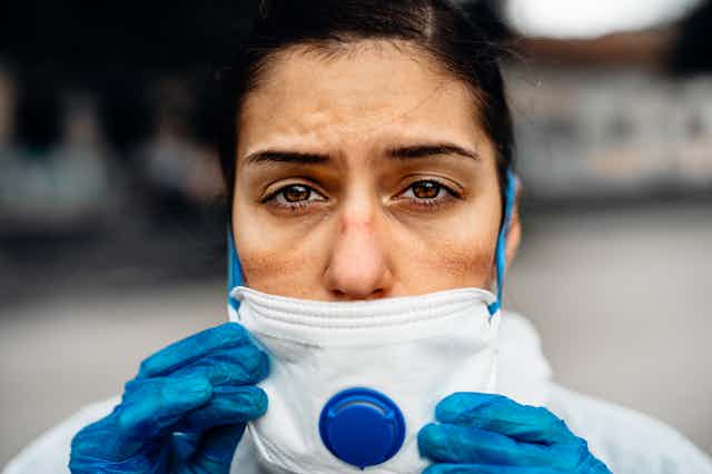 Woman in PPE looking exhausted