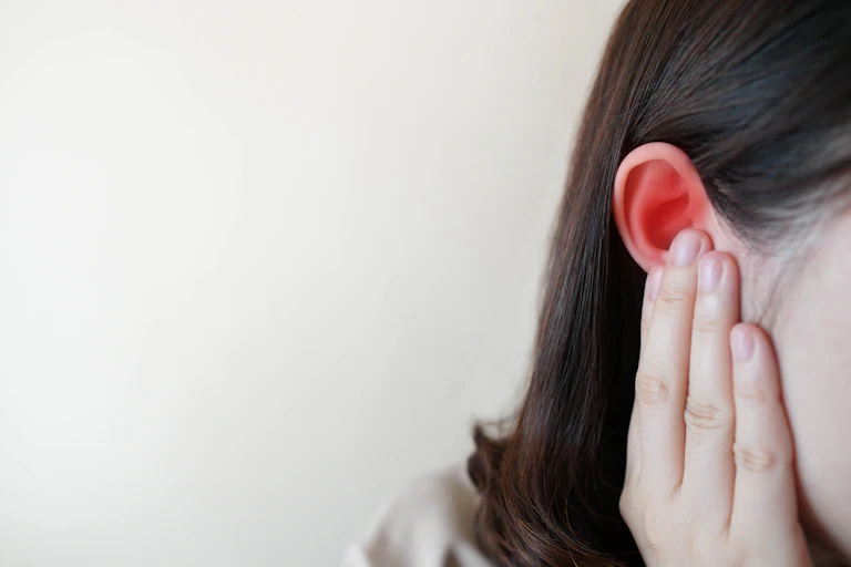 Woman holds ear.