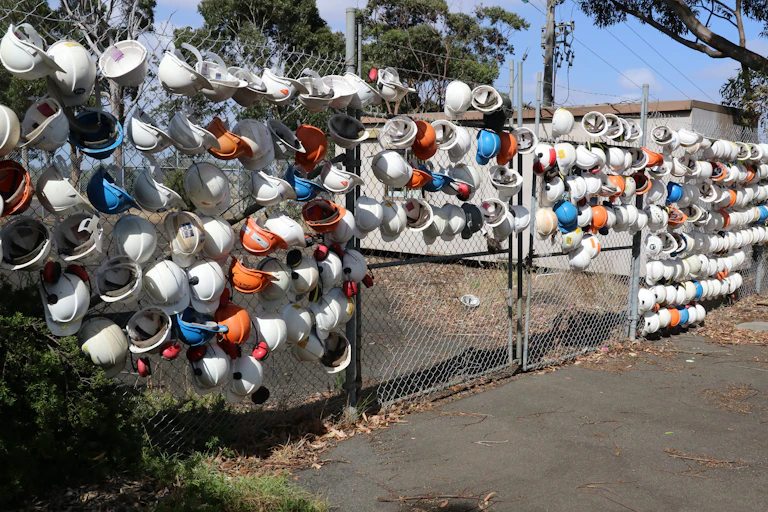 coal worker hats hanging on fence