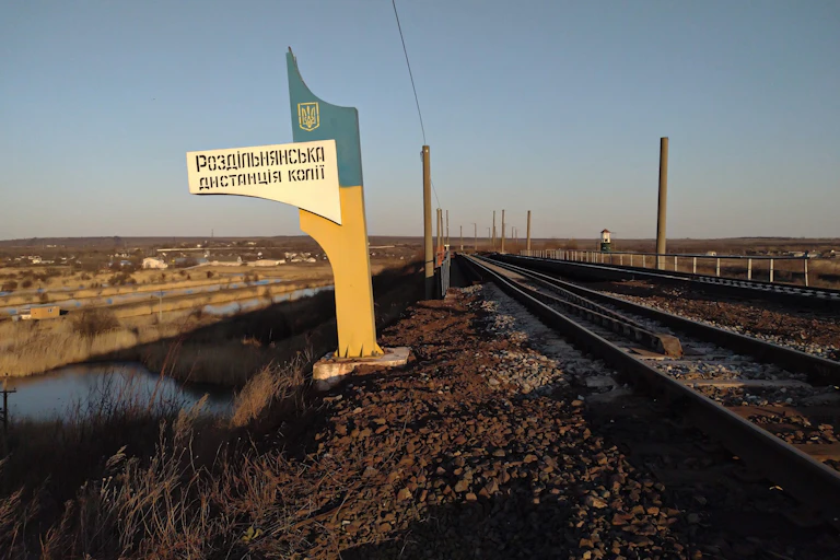A large Soviet looking sign stands next to an empty railroad track
