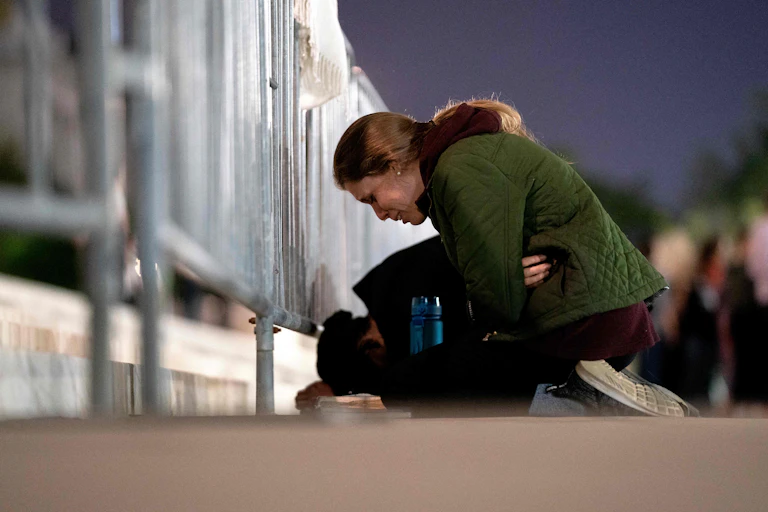 A woman in a green jacked is in tears as she kneels in front of a barrier erected outside the Supreme Court.