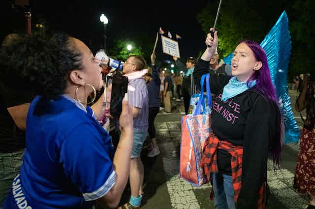 Two women arguing with each other during the night at a demonstration.