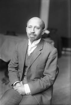 Man in suit sits in chair.