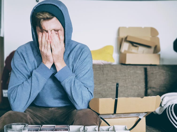 Stressed out young man covers his face with his hands.