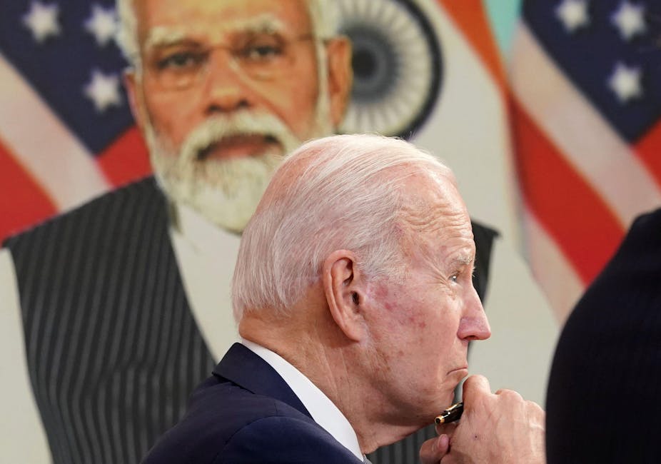 Joe Biden with Narendra Modi on the screen behind.