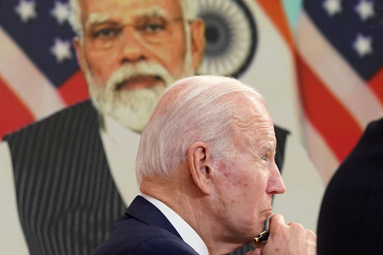Joe Biden with Narendra Modi on the screen behind.