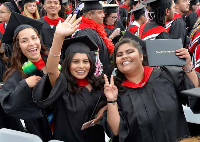 Three women of color attend their college graduation. 