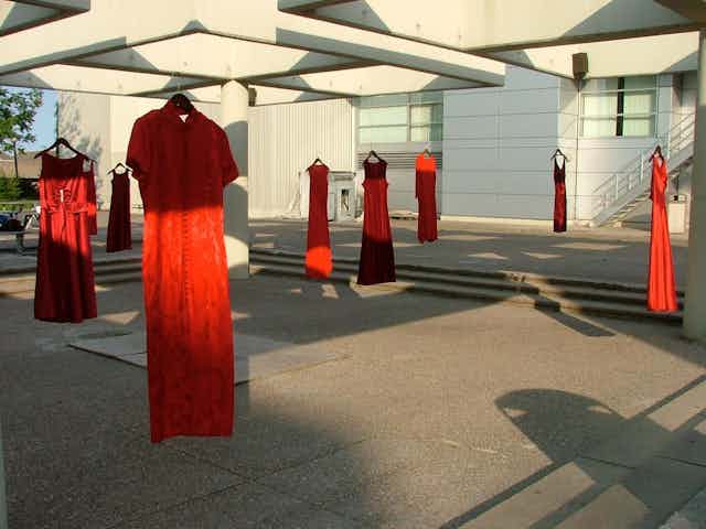 Red dresses are hung outside on a sunny day