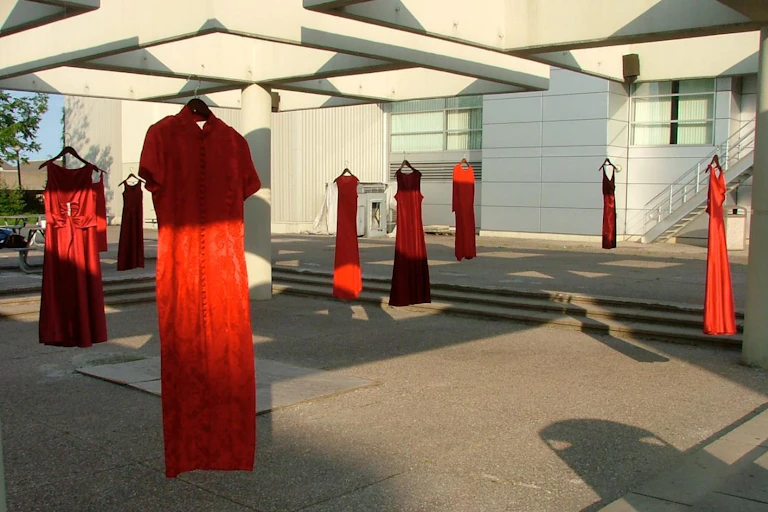 Red dresses are hung outside on a sunny day