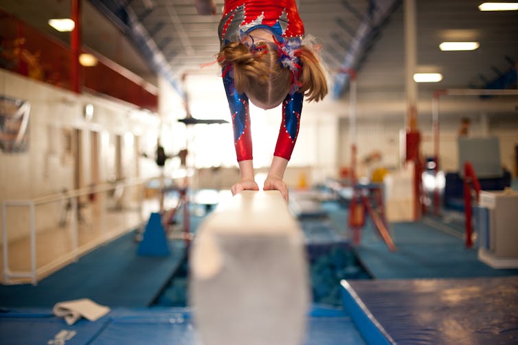 Girl doing a hand stand on balance beam