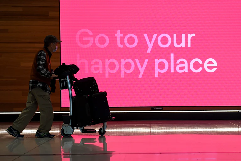 Passenger pushing baggage trolley at airport.