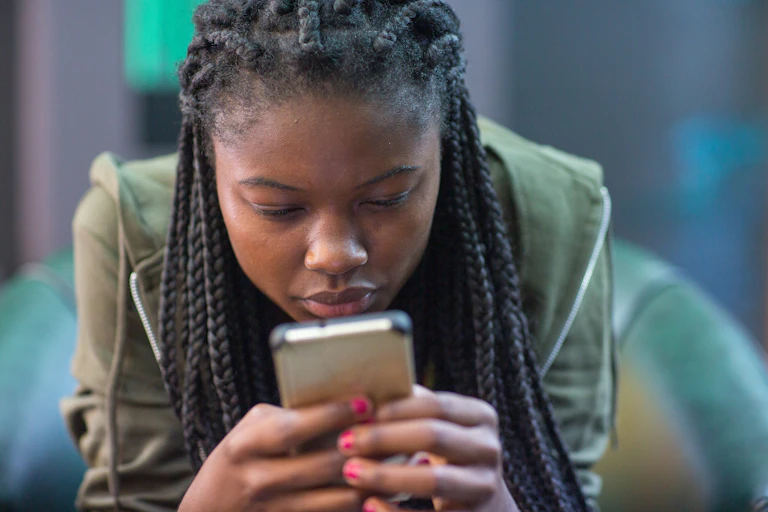 A young African woman stares intently at a cellphone