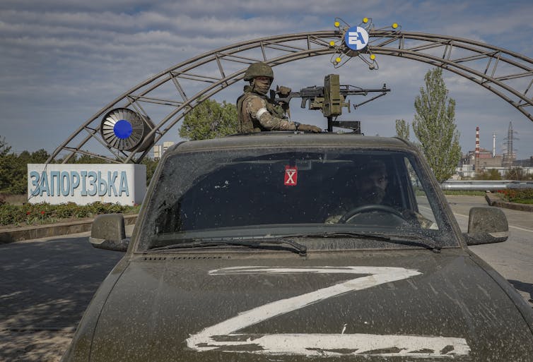 A Russian gunner stands on the back of an armoured car marked with the'Z' symbol.