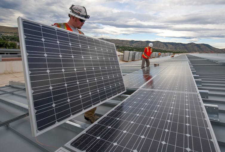 Two people install solar panels