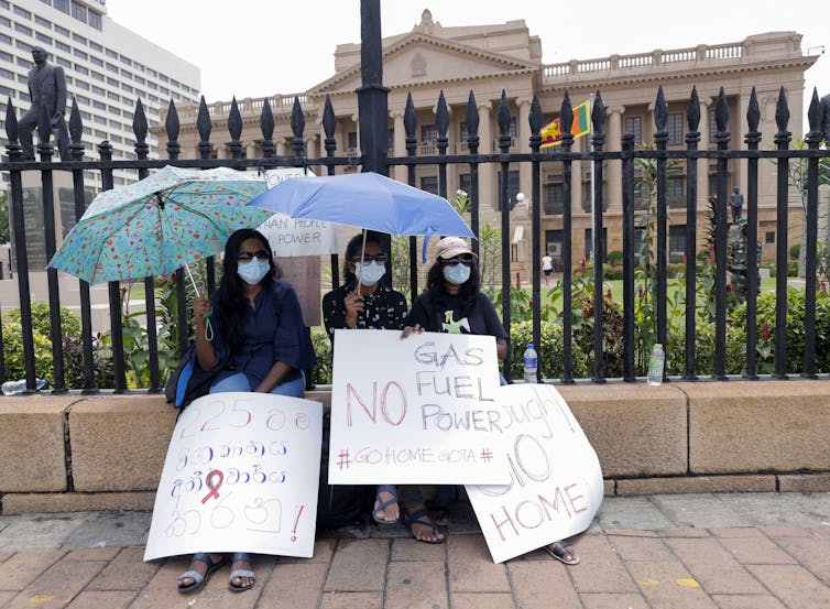 Three women with umbrellas and placards.