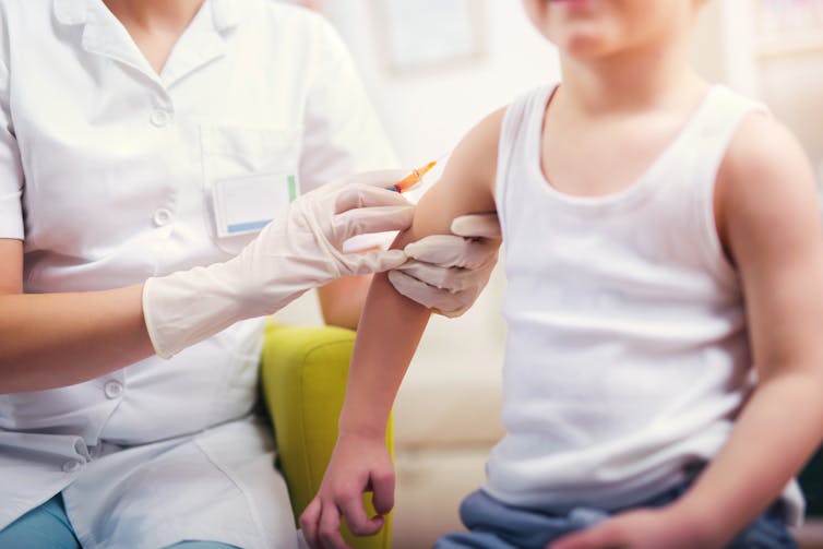 A doctor or nurse administers a vaccine to a child.