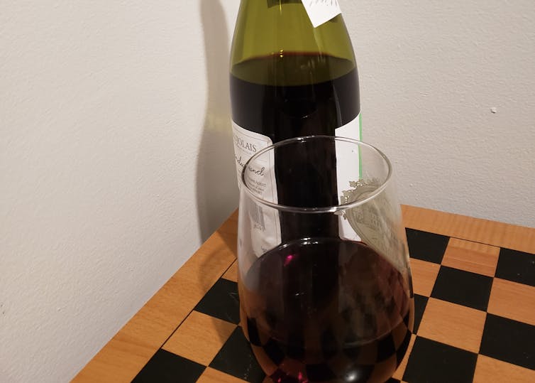 A glass of red wine in front of a bottle