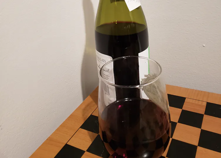 A glass of red wine in front of a bottle