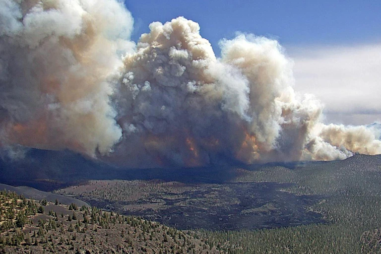 A long line of fires burning over dry hilly landscape.