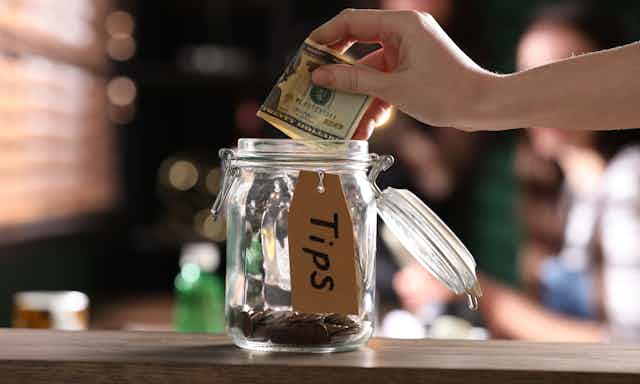 Hand putting money in a tip jar