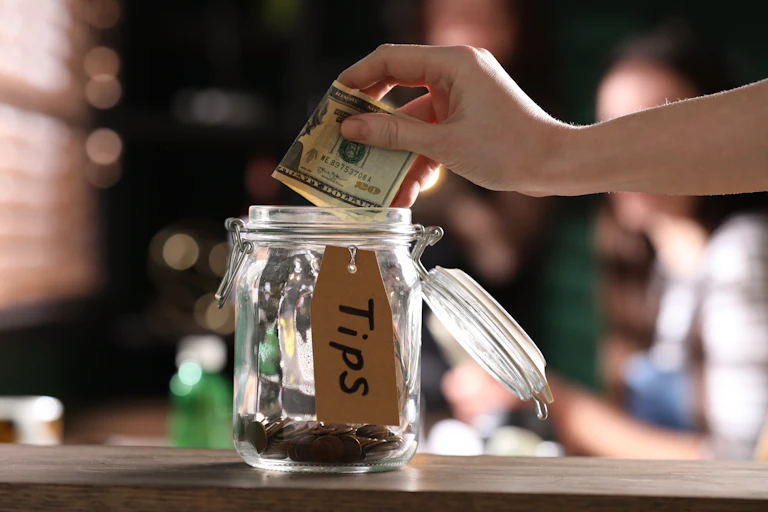 Hand putting money in a tip jar