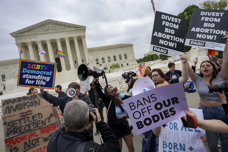 Protestors hold signs like 'divest from big abortion now' and 'LGBT Democrat standing for life' and 'Bans off our bodies' outside the US Supreme Court
