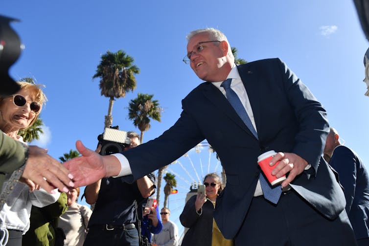 man in suit shakes hands with person in crowd