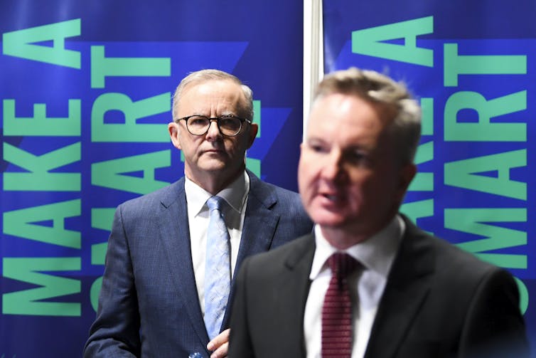 two men stand in front of signs