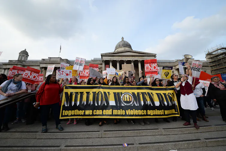 Protesters in London hold up banners against gendered violence.