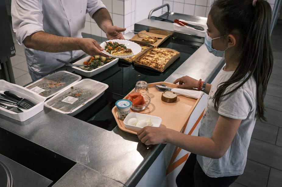Un employé sert un repas à un élève lors de son déjeuner à la cantine scolaire de l'école, à Lyon, le 28 mai 2021.