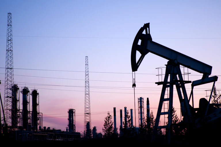 An oil pump in an industrial landscape at sunset.