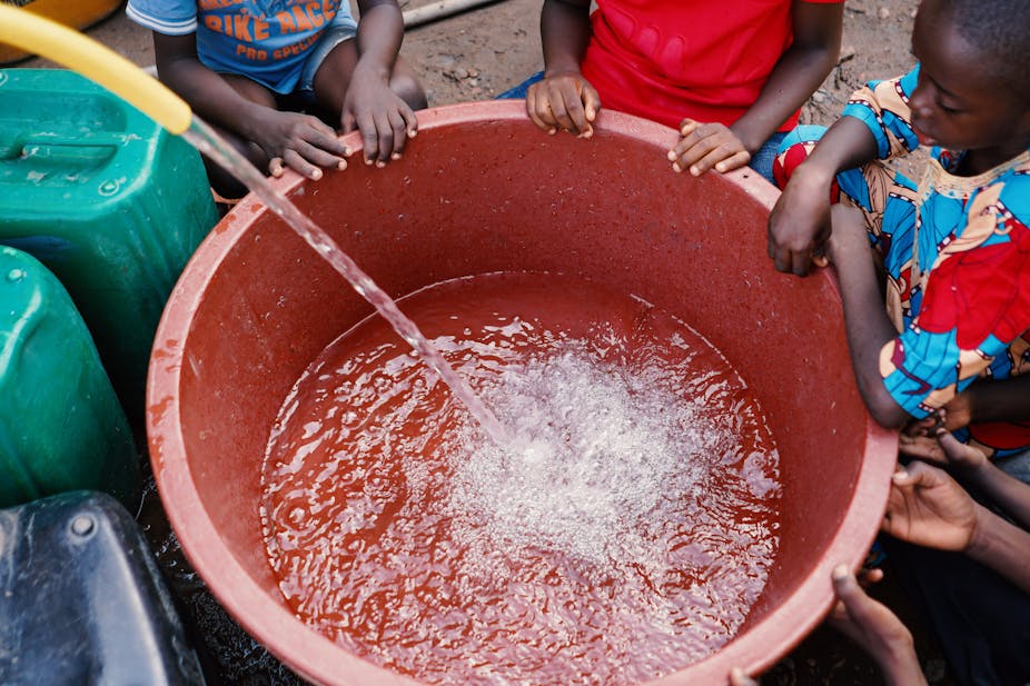 kids watching a bucket being filled with water