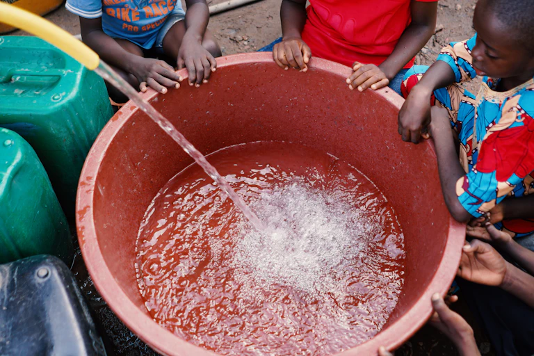 kids watching a bucket being filled with water