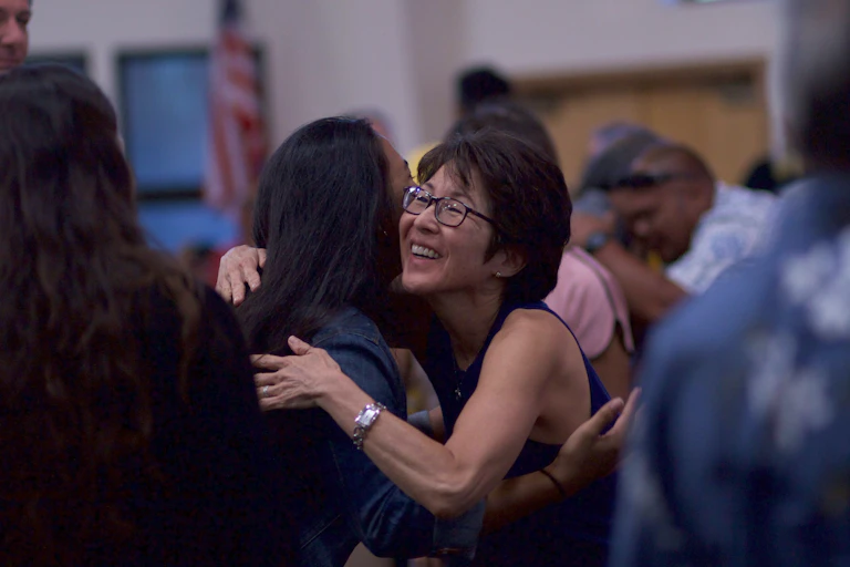 A woman hugs another