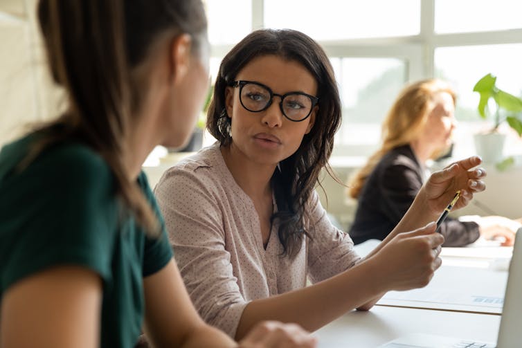 Woman at desk talking to other woman